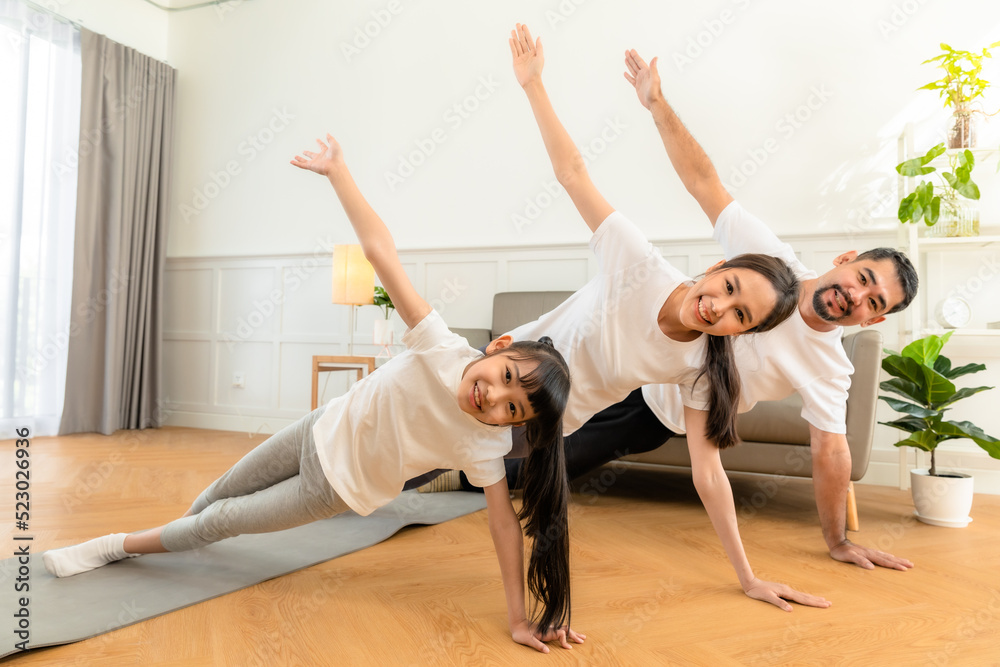 Young asian parents with child meditating at home isolated in room. Family, sport, yoga concept. Young asian parents with child meditating at home isolated in room. Family, sport, yoga concept.