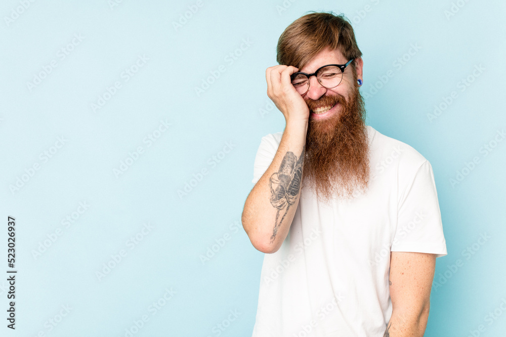 Young caucasian red-haired man isolated on blue background laughing happy, carefree, natural emotion.