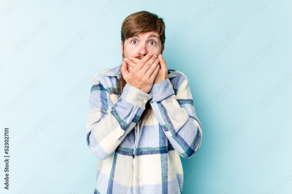 Young caucasian red-haired man isolated on blue background covering mouth with hands looking worried. Young caucasian red-haired man isolated on blue background covering mouth with hands looking worried.