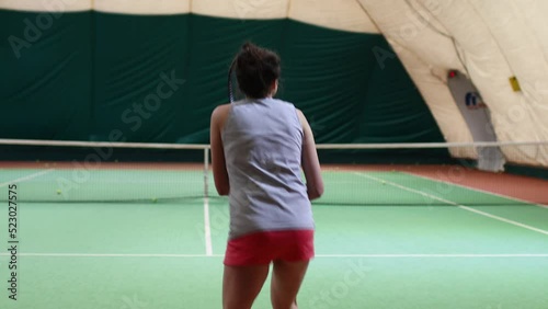 Tennis woman player playing training with racket and ball at court. Back view