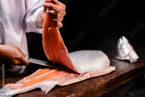 Photography Chef's hand holding fresh piece of salmon
