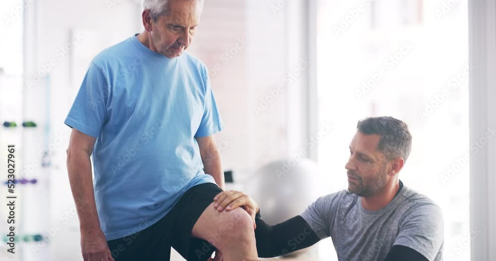 Male physiotherapy professional taking care and stretching a senior patient to help with a leg injury. An old man doing a physical therapy exercise. Healthcare worker helping a elderly male stretch