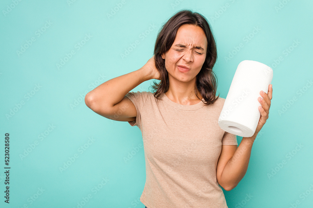 Young hispanic woman holding kitchen roll isolated on blue background touching back of head, thinking and making a choice. Young hispanic woman holding kitchen roll isolated on blue background touching back of head, thinking and making a choice.