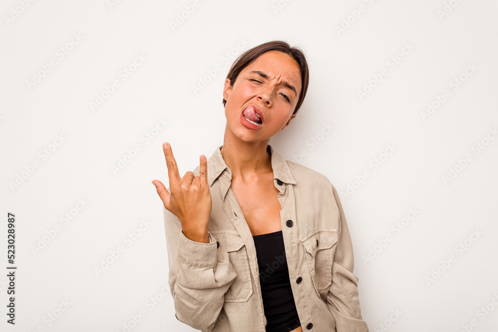 Young hispanic woman isolated on white background showing rock gesture with fingers Young hispanic woman isolated on white background showing rock gesture with fingers