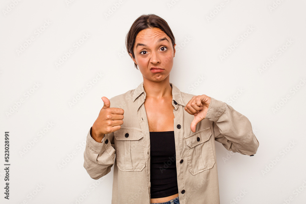 Young hispanic woman isolated on white background showing thumbs up and thumbs down, difficult choose concept Young hispanic woman isolated on white background showing thumbs up and thumbs down, difficult choose concept