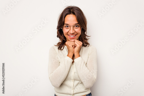 Young hispanic woman isolated on white background keeps hands under chin, is looking happily aside.