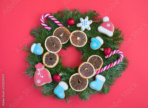 Christmas ring or wreath with gingerbread and dried orange on the red background. Top view. Close-up.