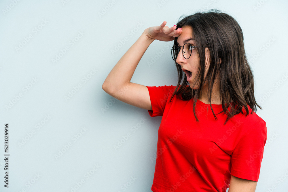 Young caucasian woman isolated on blue background looking far away keeping hand on forehead. Young caucasian woman isolated on blue background looking far away keeping hand on forehead.