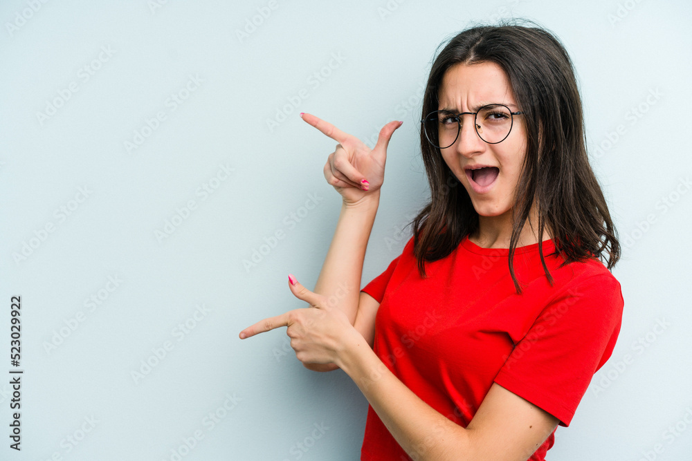 Young caucasian woman isolated on blue background excited pointing with forefingers away. Young caucasian woman isolated on blue background excited pointing with forefingers away.