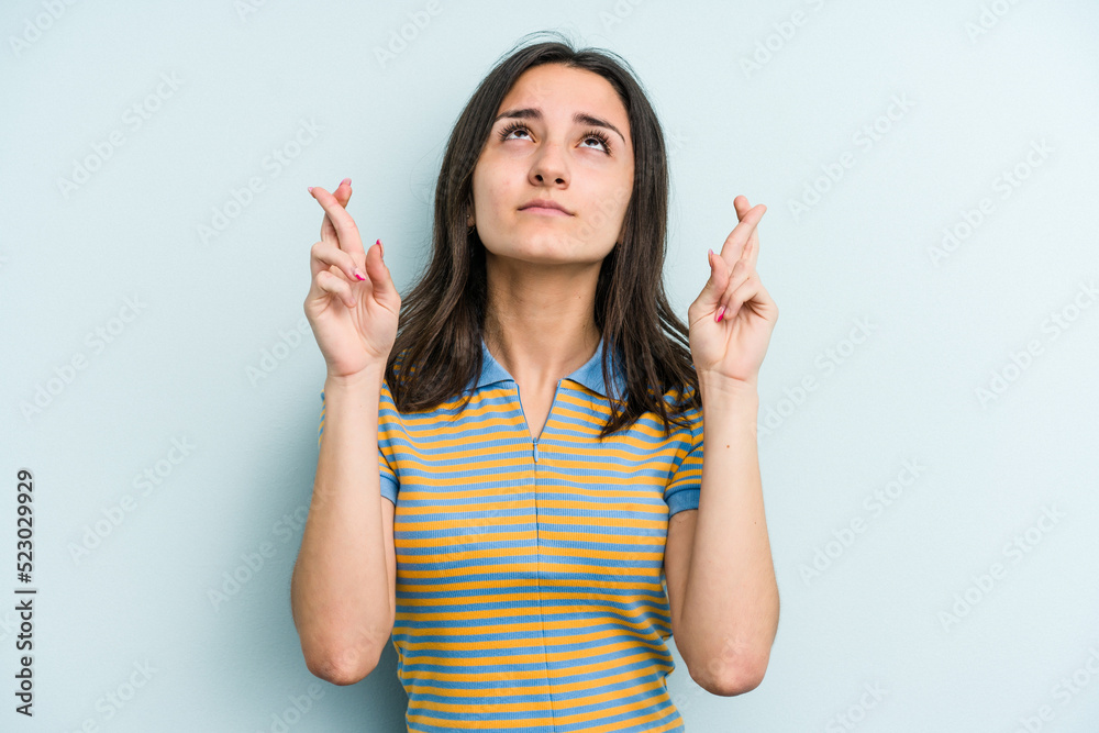 Young caucasian woman isolated on blue background crossing fingers for having luck Young caucasian woman isolated on blue background crossing fingers for having luck