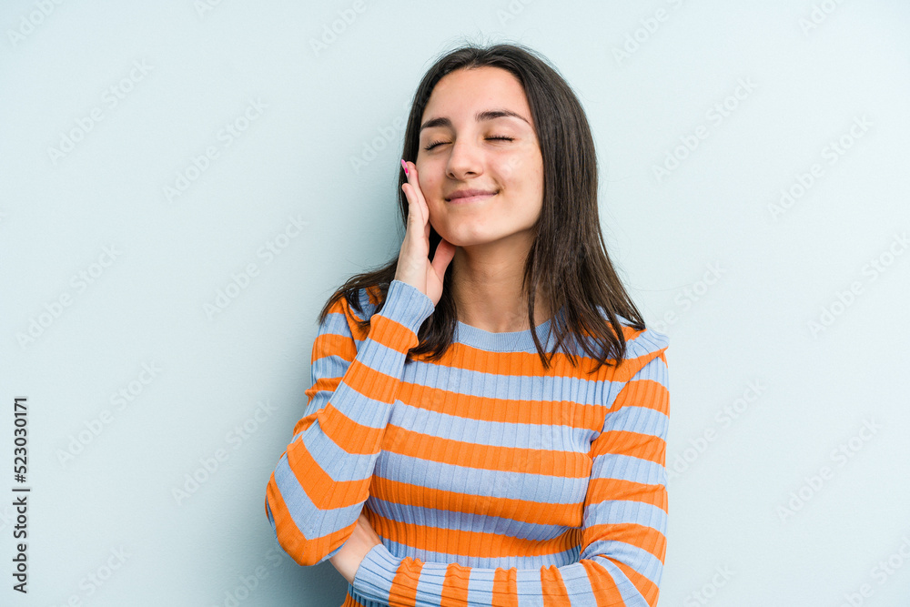Young caucasian woman isolated on blue background laughs happily and has fun keeping hands on stomach. Young caucasian woman isolated on blue background laughs happily and has fun keeping hands on stomach.