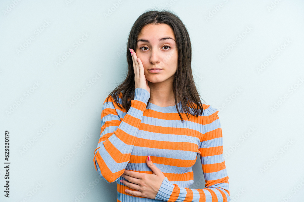 Young caucasian woman isolated on blue background blows cheeks, has tired expression. Facial expression concept.