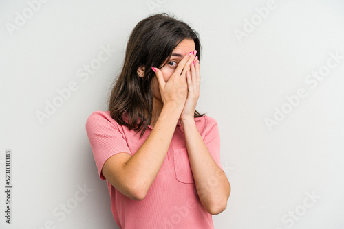 Young caucasian woman isolated on white background blink through fingers frightened and nervous. © Asier