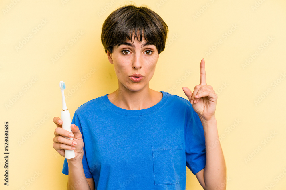 Young caucasian woman holding a electric toothbrush isolated on yellow background having an idea, inspiration concept. Young caucasian woman holding a electric toothbrush isolated on yellow background having an idea, inspiration concept.