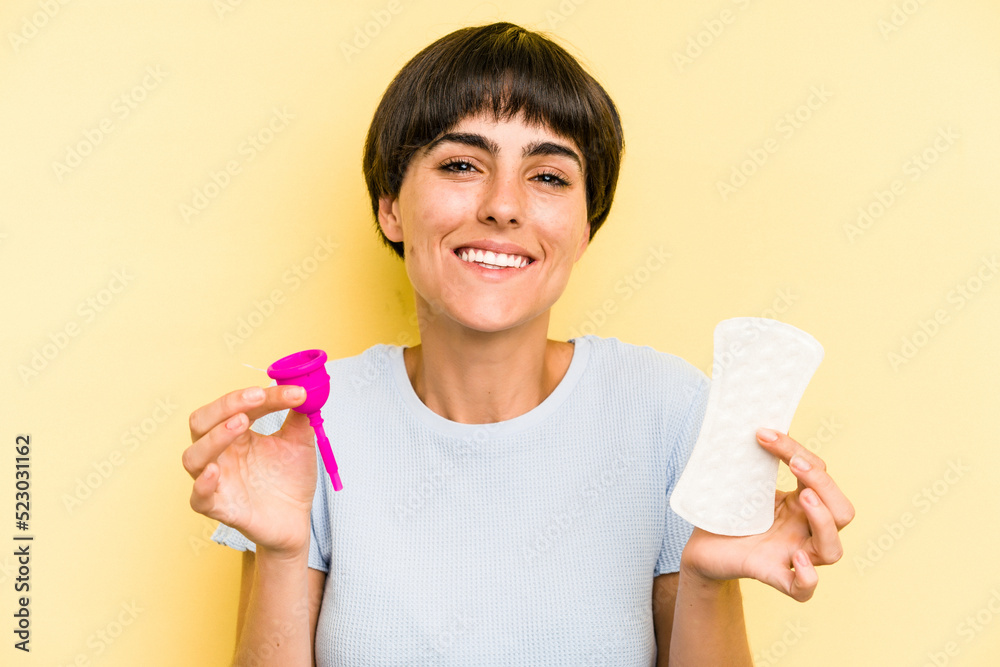 Young caucasian woman holding a menstrual cup isolated on yellow background Young caucasian woman holding a menstrual cup isolated on yellow background