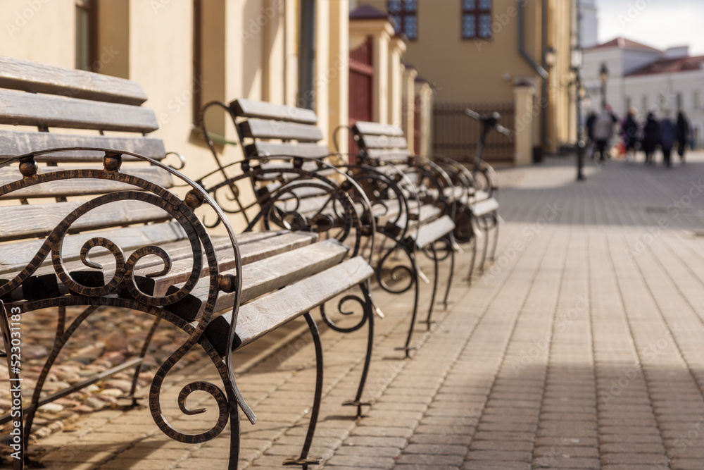 row of benches on an old street in the city, sunny summer day, copy space