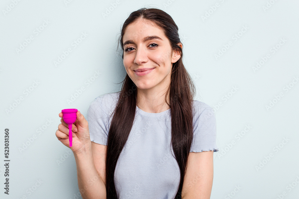 Young caucasian woman holding a sanitary napkin isolated on blue background laughing and having fun. Young caucasian woman holding a sanitary napkin isolated on blue background laughing and having fun.