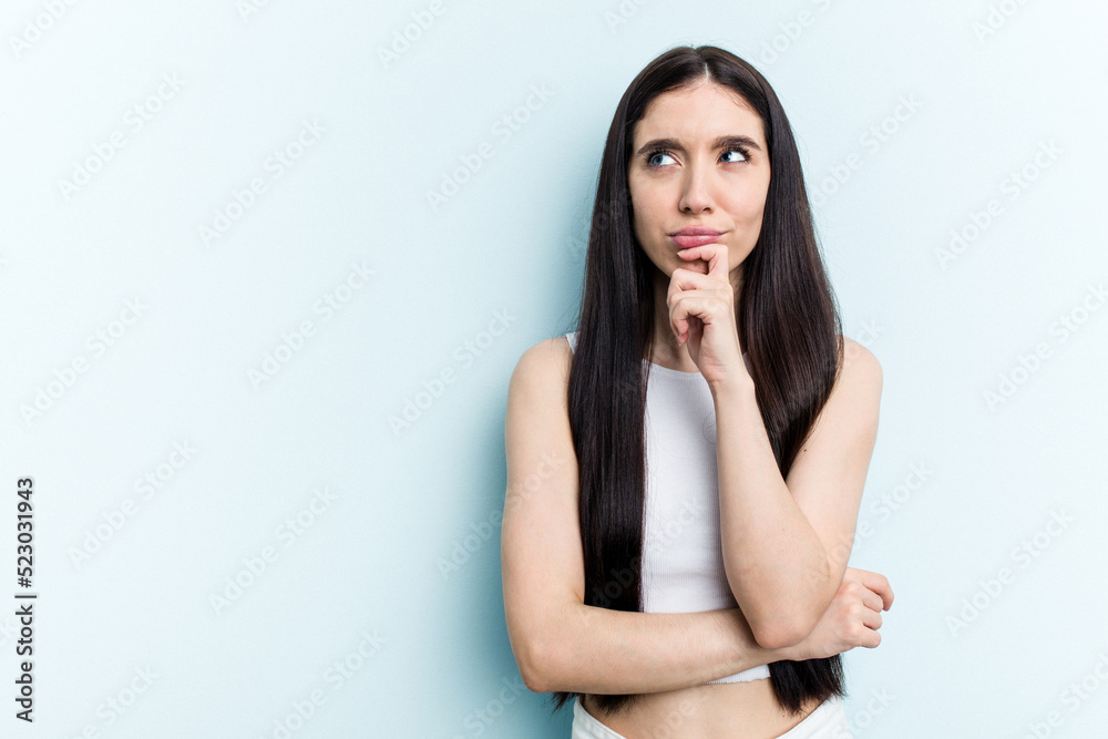 Young caucasian woman isolated on blue background looking sideways with doubtful and skeptical expression. Young caucasian woman isolated on blue background looking sideways with doubtful and skeptical expression.