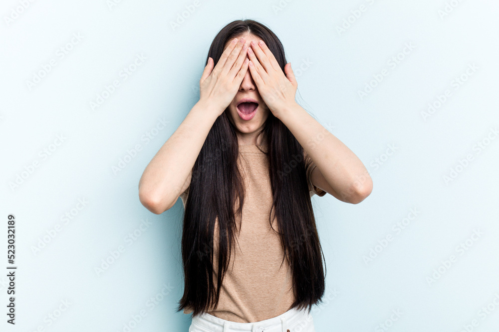 Young caucasian woman isolated on blue background having fun covering half of face with palm. Young caucasian woman isolated on blue background having fun covering half of face with palm.