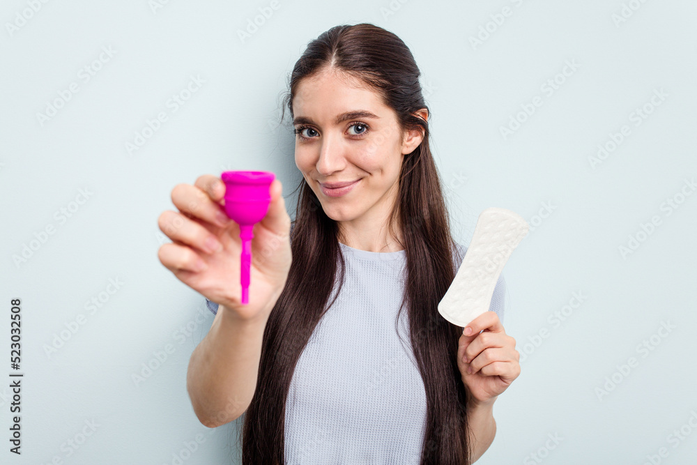 Young caucasian woman holding a menstrual cup isolated on blue background Young caucasian woman holding a menstrual cup isolated on blue background
