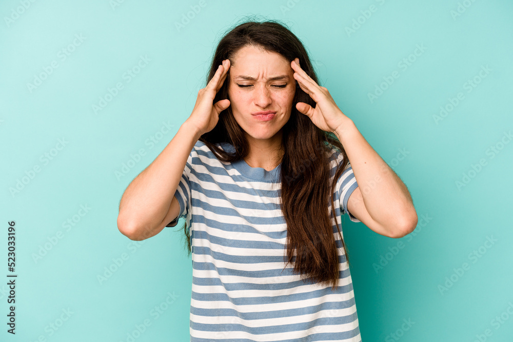 Young caucasian woman isolated on blue background touching temples and having headache. Young caucasian woman isolated on blue background touching temples and having headache.