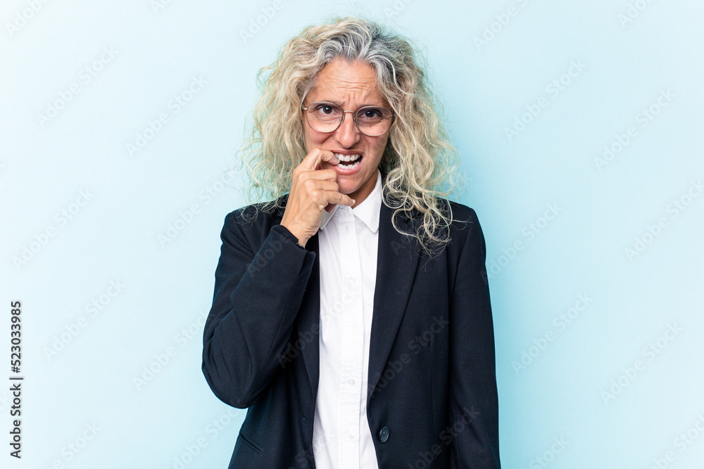 Middle age caucasian business woman isolated on blue background biting fingernails, nervous and very anxious. Middle age caucasian business woman isolated on blue background biting fingernails, nervous and very anxious.