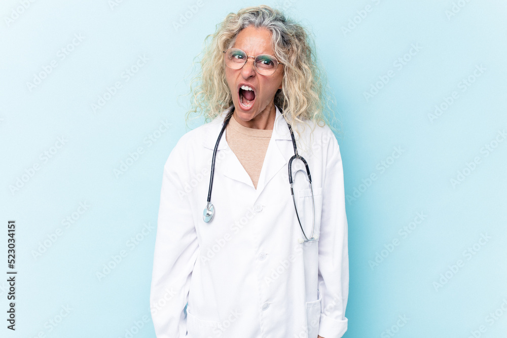 Middle age caucasian woman isolated on blue background screaming very angry and aggressive. Middle age caucasian woman isolated on blue background screaming very angry and aggressive.