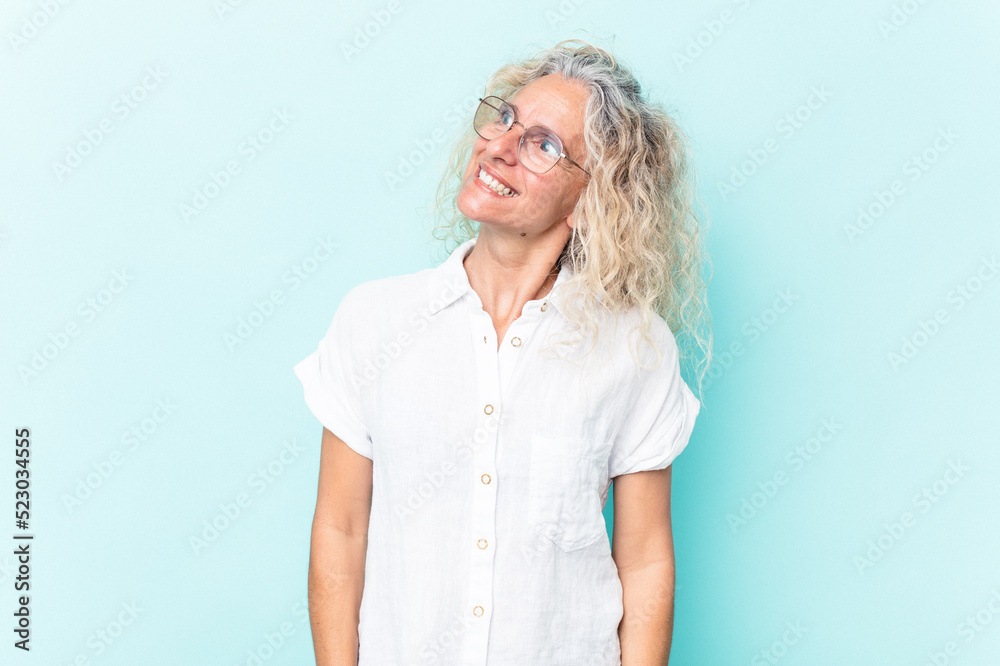 Middle age caucasian woman isolated on blue background relaxed and happy laughing, neck stretched showing teeth.