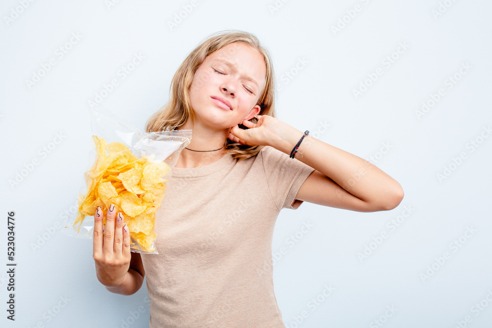 Caucasian teen girl holding bag of chips isolated on blue background touching back of head, thinking and making a choice. Caucasian teen girl holding bag of chips isolated on blue background touching back of head, thinking and making a choice.