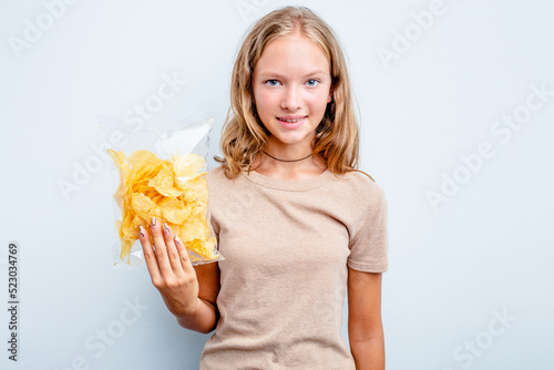 Caucasian teen girl holding bag of chips isolated on blue background happy  smiling and cheerful.