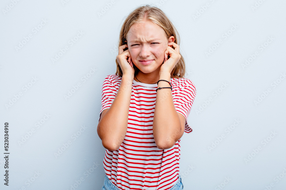 Caucasian teen girl isolated on blue background covering ears with fingers, stressed and desperate by a loudly ambient. Caucasian teen girl isolated on blue background covering ears with fingers, stressed and desperate by a loudly ambient.