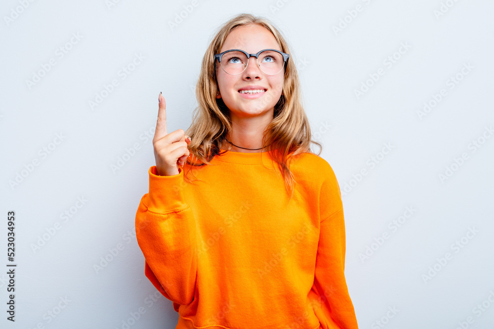 Caucasian teen girl isolated on blue background indicates with both fore fingers up showing a blank space.