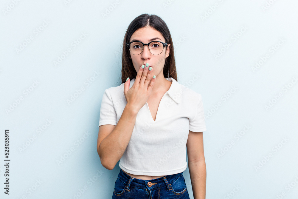 Young caucasian woman isolated on blue background shocked, covering mouth with hands, anxious to discover something new.