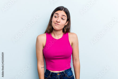 Young caucasian woman isolated on blue background shrugs shoulders and open eyes confused.