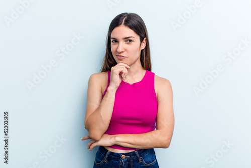 Young caucasian woman isolated on blue background thinking and looking up, being reflective, contemplating, having a fantasy.