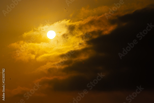 orange horizon with sun and clouds, shot with telephoto lens