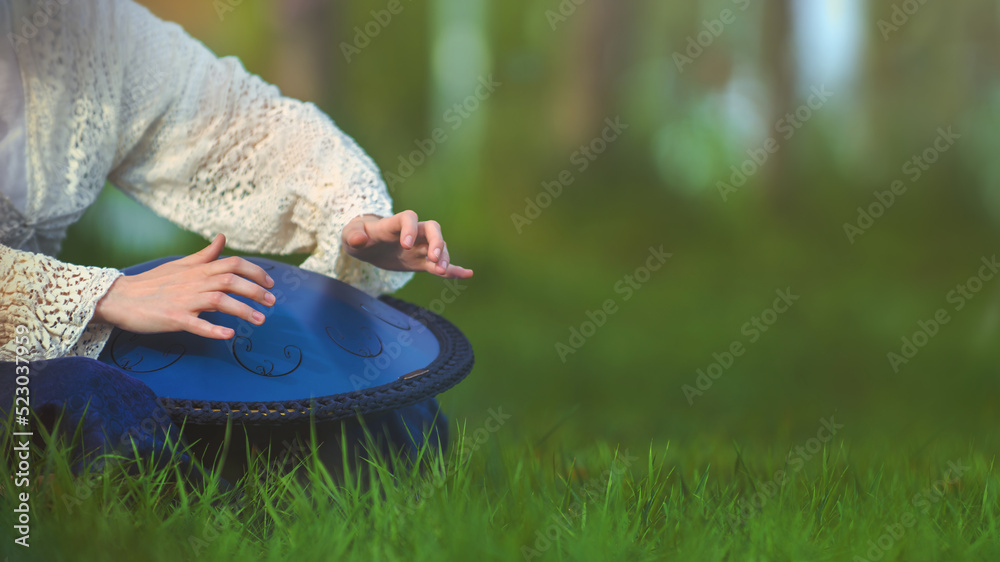 Female hands playing a tongue drum musical instrument (metal drum with