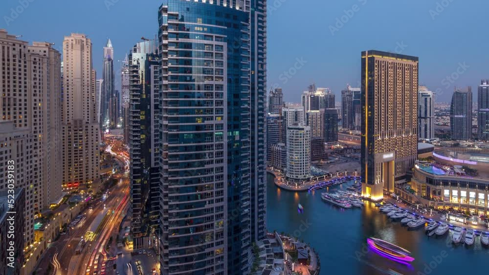 Evening illumination of Dubai Marina day to night transition aerial timelapse, UAE. Modern skyscrapers and residential buildings. Yachts and boats near shoping mall on artificial canal city Evening illumination of Dubai Marina day to night transition aerial timelapse, UAE. Modern skyscrapers and residential buildings. Yachts and boats near shoping mall on artificial canal city