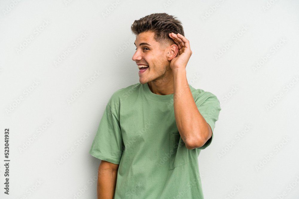 Young caucasian man isolated on white background trying to listening a gossip. Young caucasian man isolated on white background trying to listening a gossip.