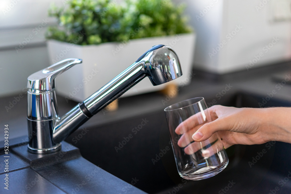 Filling a glass with drinking water from the kitchen faucet Filling a glass with drinking water from the kitchen faucet