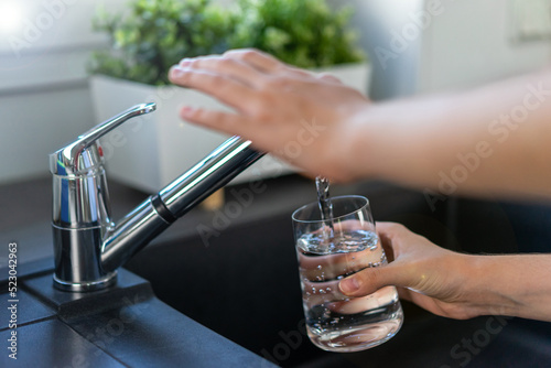 Woman's hand turns off the tap in the kitchen. Water saving concepts