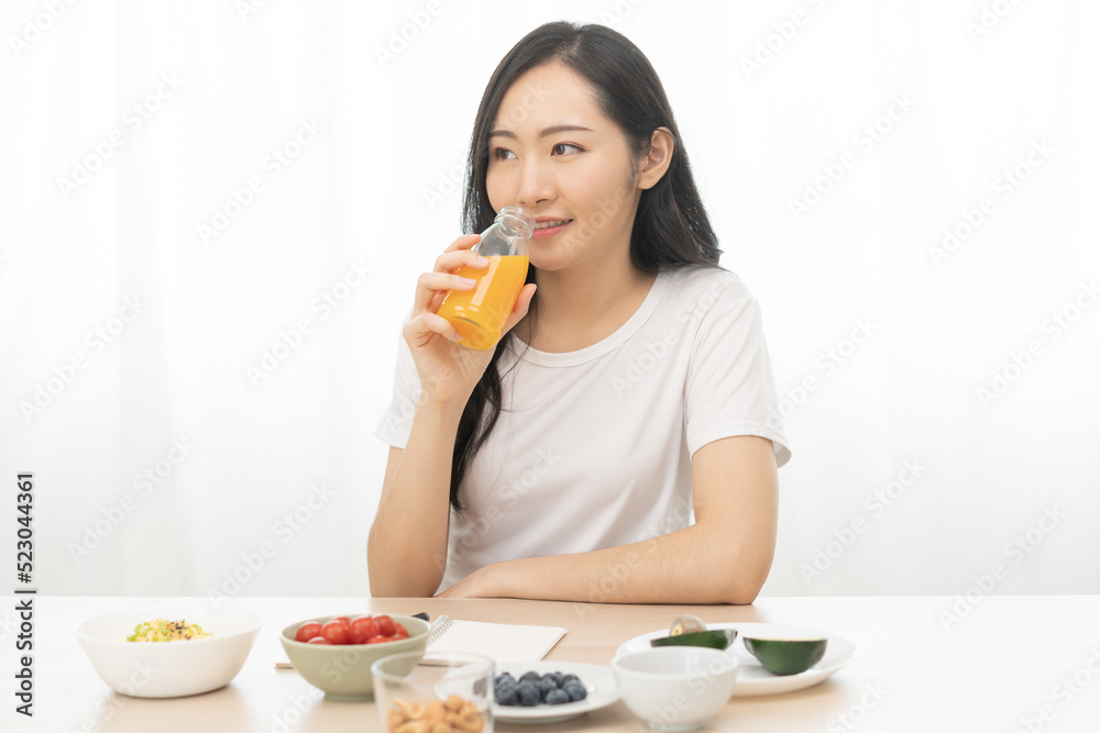 Happy smile asian young woman, girl drinking fresh orange juice in a glass bottle, holding transparent glass in hand, thirsty at home. Healthcare, healthy diet concept, isolated on white background. Happy smile asian young woman, girl drinking fresh orange juice in a glass bottle, holding transparent glass in hand, thirsty at home. Healthcare, healthy diet concept, isolated on white background.