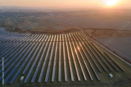 Aerial view of big sustainable electric power plant with many rows of solar photovoltaic panels for producing clean electrical energy at sunset. Renewable electricity with zero emission concept