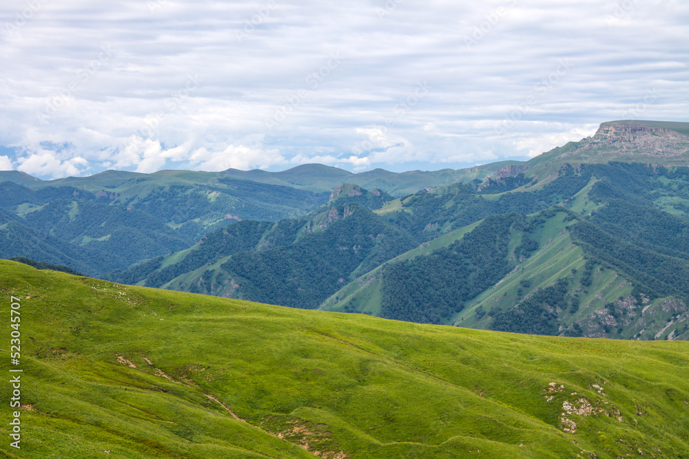 Beautiful landscape - panoramic view of green mountains and hills blurred in morning haze from bermamyt plateau in karachay-cherkessia Russia and dramatic clouds and copy space