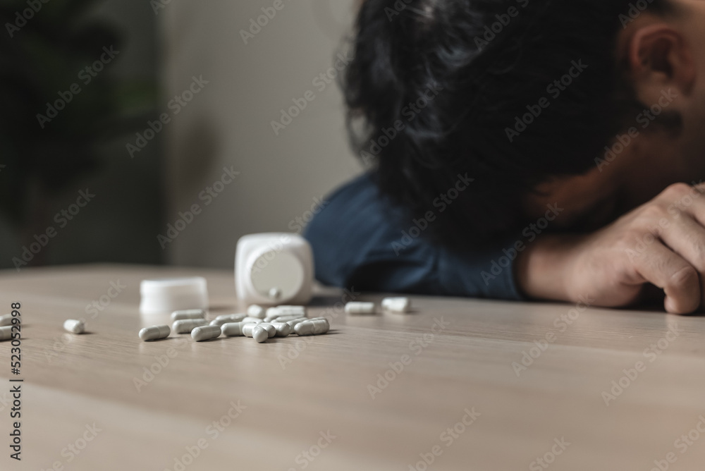 the person using drug overdoses lying on the table. close up on pills in hand. the person using drug overdoses lying on the table. close up on pills in hand.