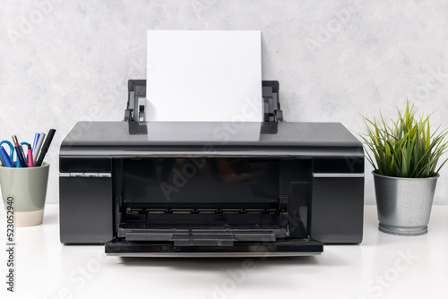 Inkjet printer with blank paper sheet on office desk. Template mock up photo