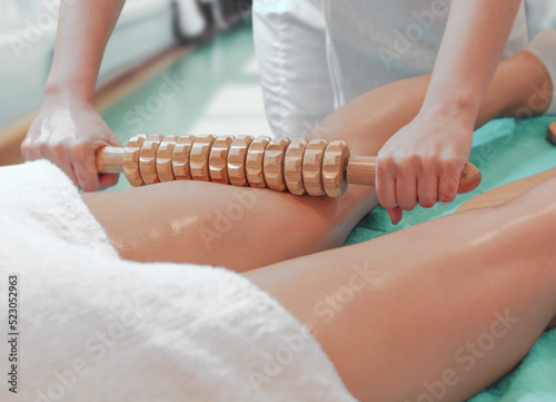 Close up of woman during spa anti cellulite massage with rolling pin or battledore