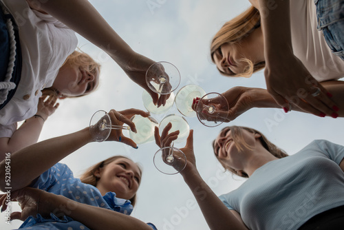 Fotografía Bottom view of group of young smiling attractive women holding clinking glasses with white wine champagne, celebrating