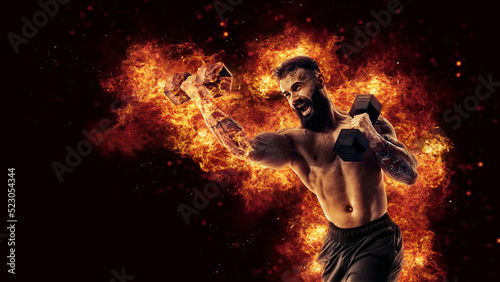 Handsome bearded shirtless tattooed bodybuilder workout wih dumbbell like boxer. Fire art concept © zamuruev