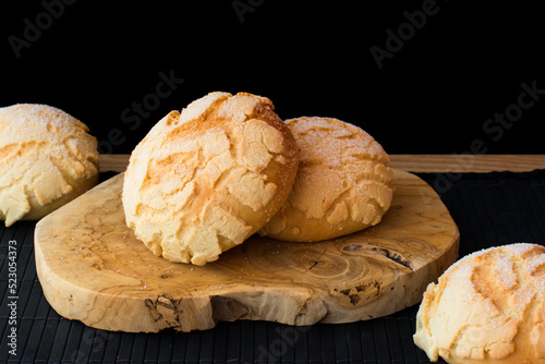 Melon pan, comida japonesa. Bollo de pan dulce con capa crujiente por encima sobre madera y fondo negro. photo